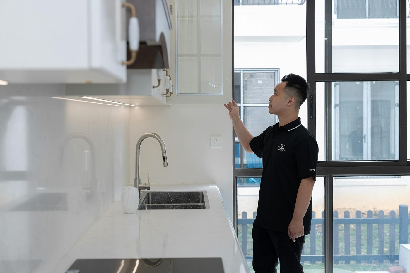 A tenant in an empty flat checks a handover list and photographs the kitchen condition