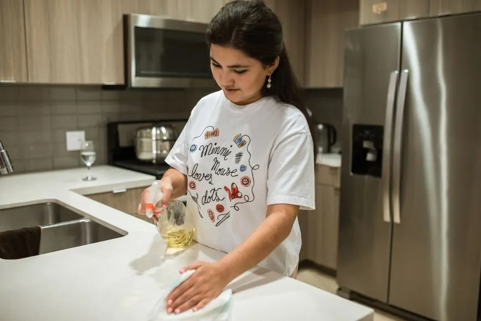 Žena nejprve mechanicky otírá kuchyňskou pracovní desku a používá prostředek pouze na určenou plochu.