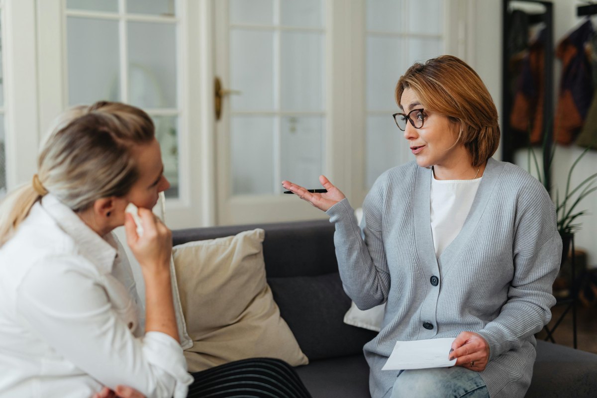 Two women talk calmly in a flat while resetting the terms of an ongoing cleaning relationship.