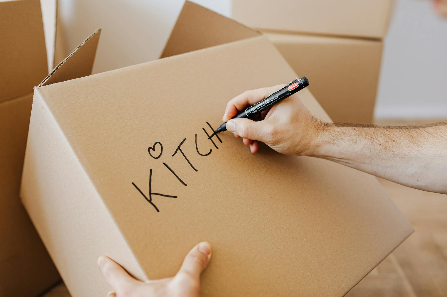 Writing labels on cardboard boxes during organized apartment packing