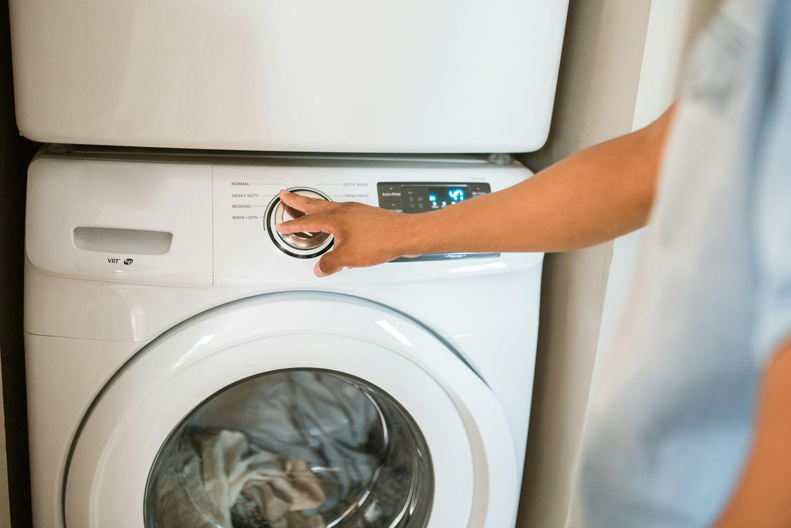 Person cleaning around a front-loading washing machine at home