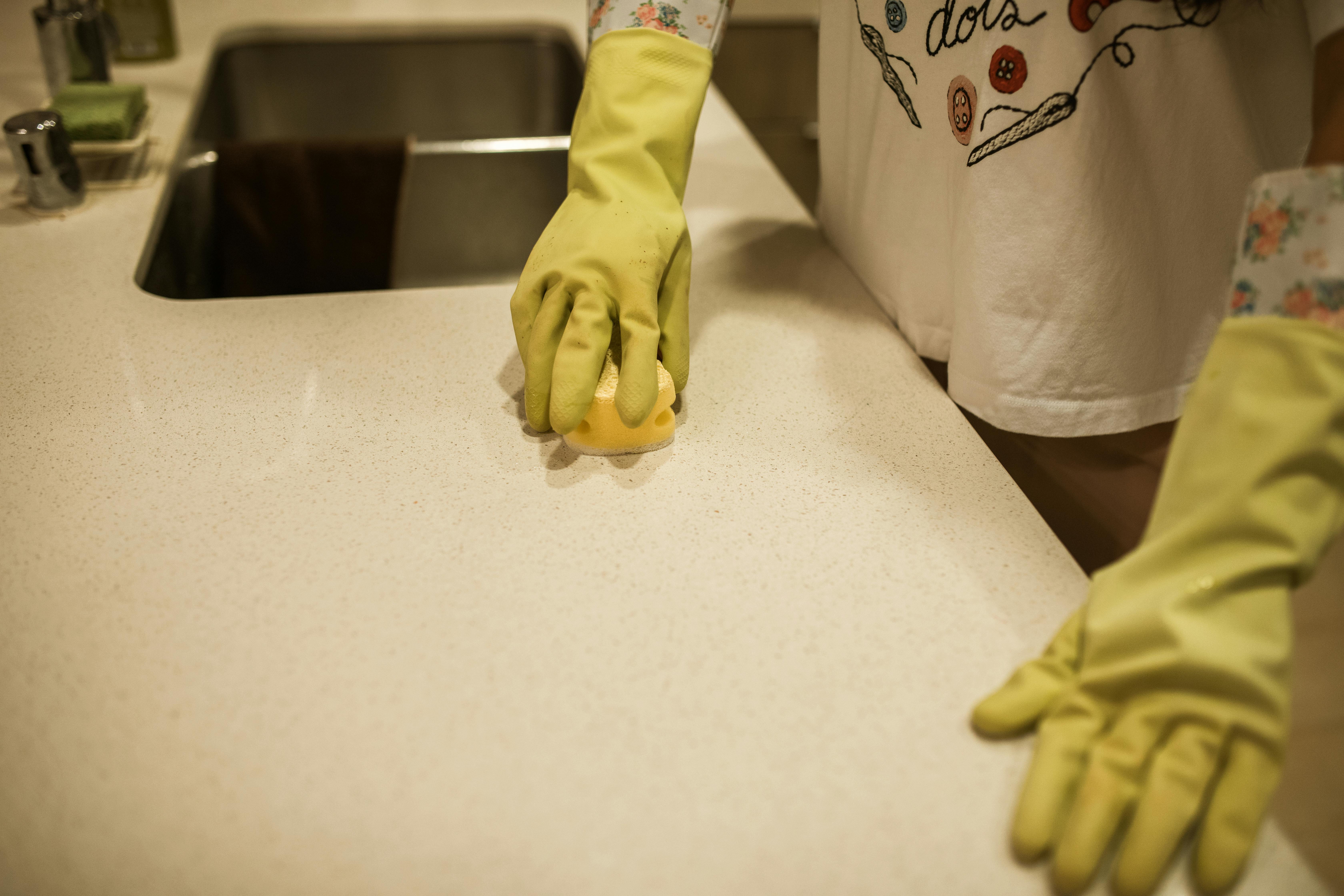 Hands in gloves cleaning a kitchen counter after Easter dining