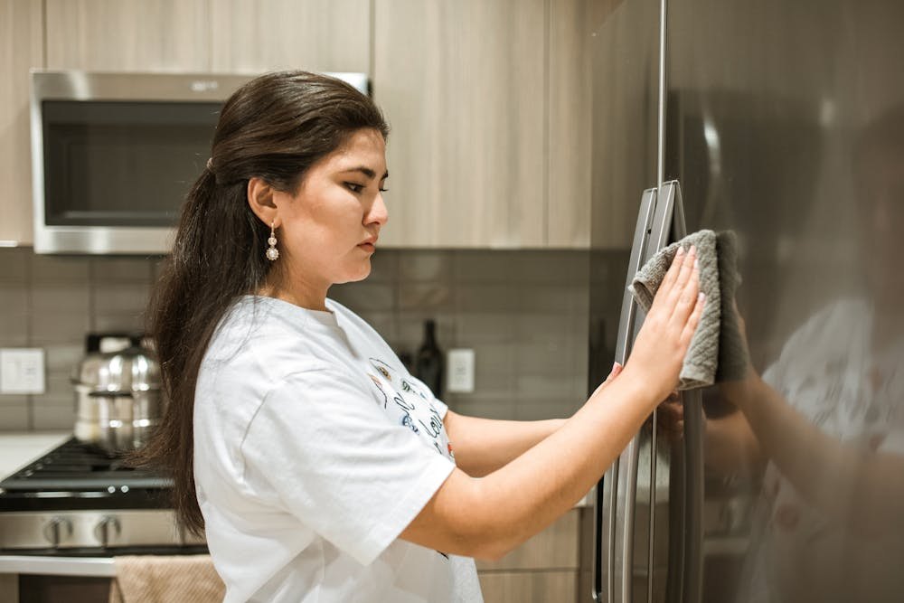 Cleaner working inside a fridge, a good example of hidden add-on work outside a routine scope.