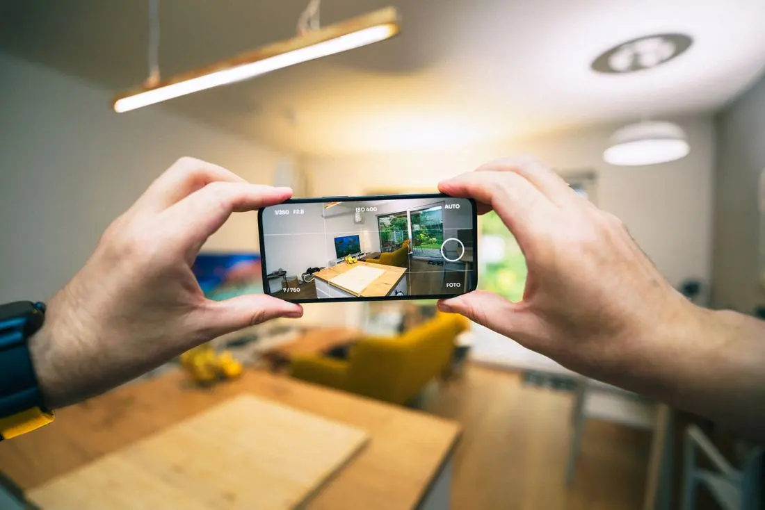 Člověk fotografuje mobilem stav bytu pro přesnější odhad úklidu