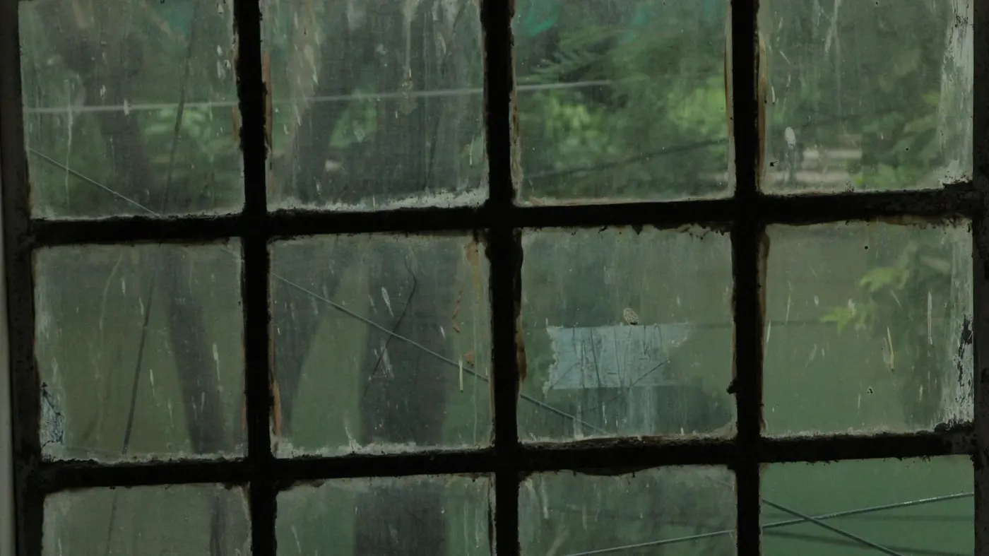 Detail zašpiněného okenního skla s viditelnými šmouhami a usazeninami.