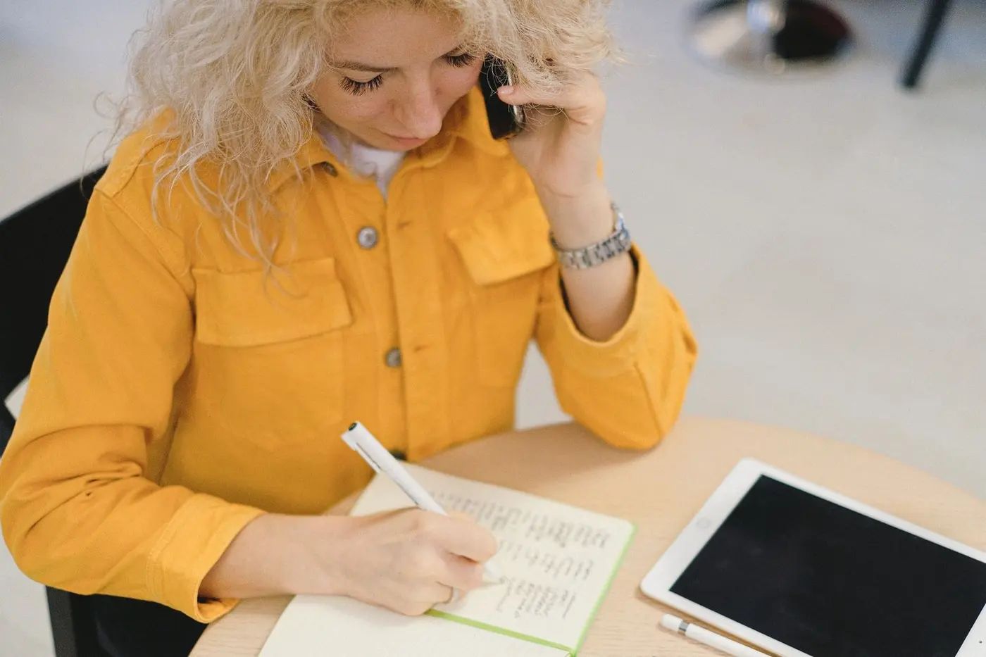 Holiday cleaning schedule planning Žena během pracovního telefonátu zapisuje prosincové termíny do plánovače na stole.