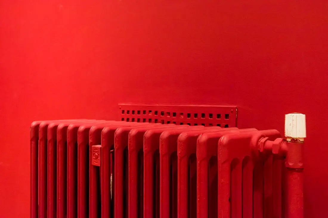 Detail článkového radiátoru s lamelami, horní mřížkou, ventilem a přívodní trubkou.