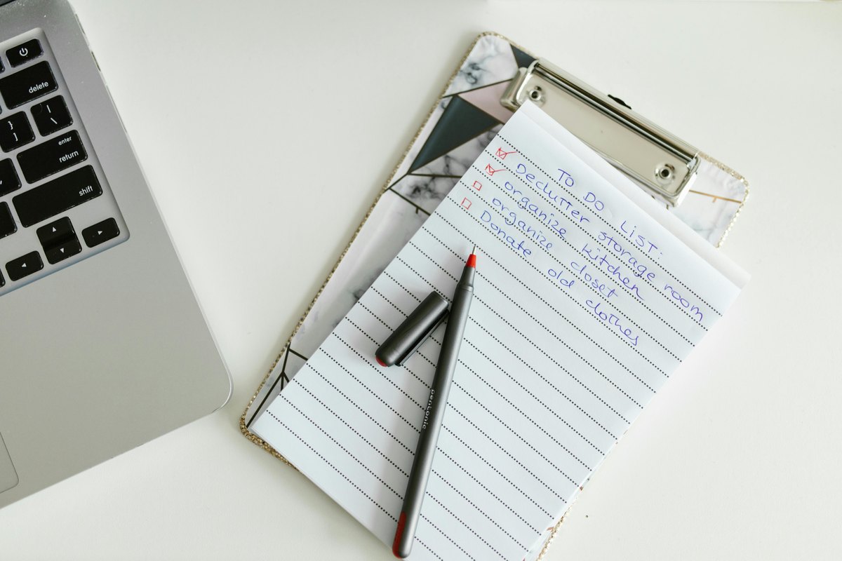 Poznámkový blok s perem a notebookem ukazuje přípravu jasných podmínek před úklidem.