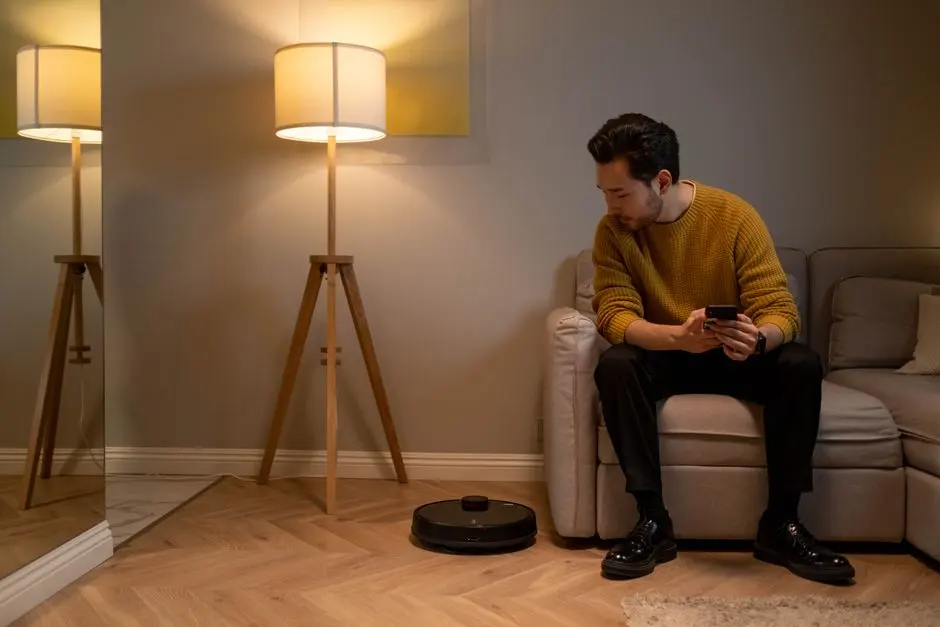 Žena ovládající robotický vysavač pomocí chytrého telefonu v moderním obývacím pokoji.