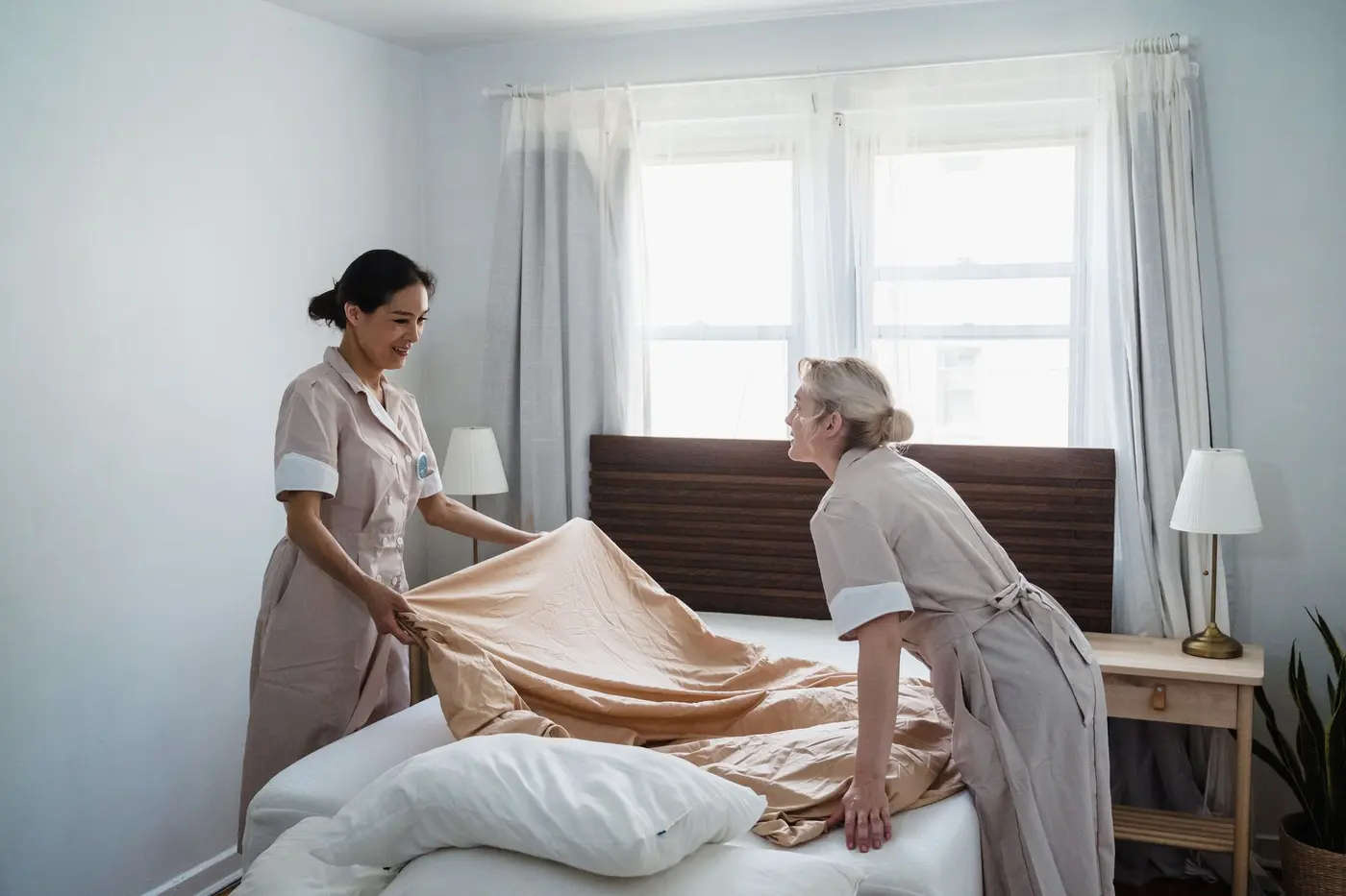 Profesionální uklízečky připravují čisté lůžko před příjezdem dalších hostů do městského apartmánu.