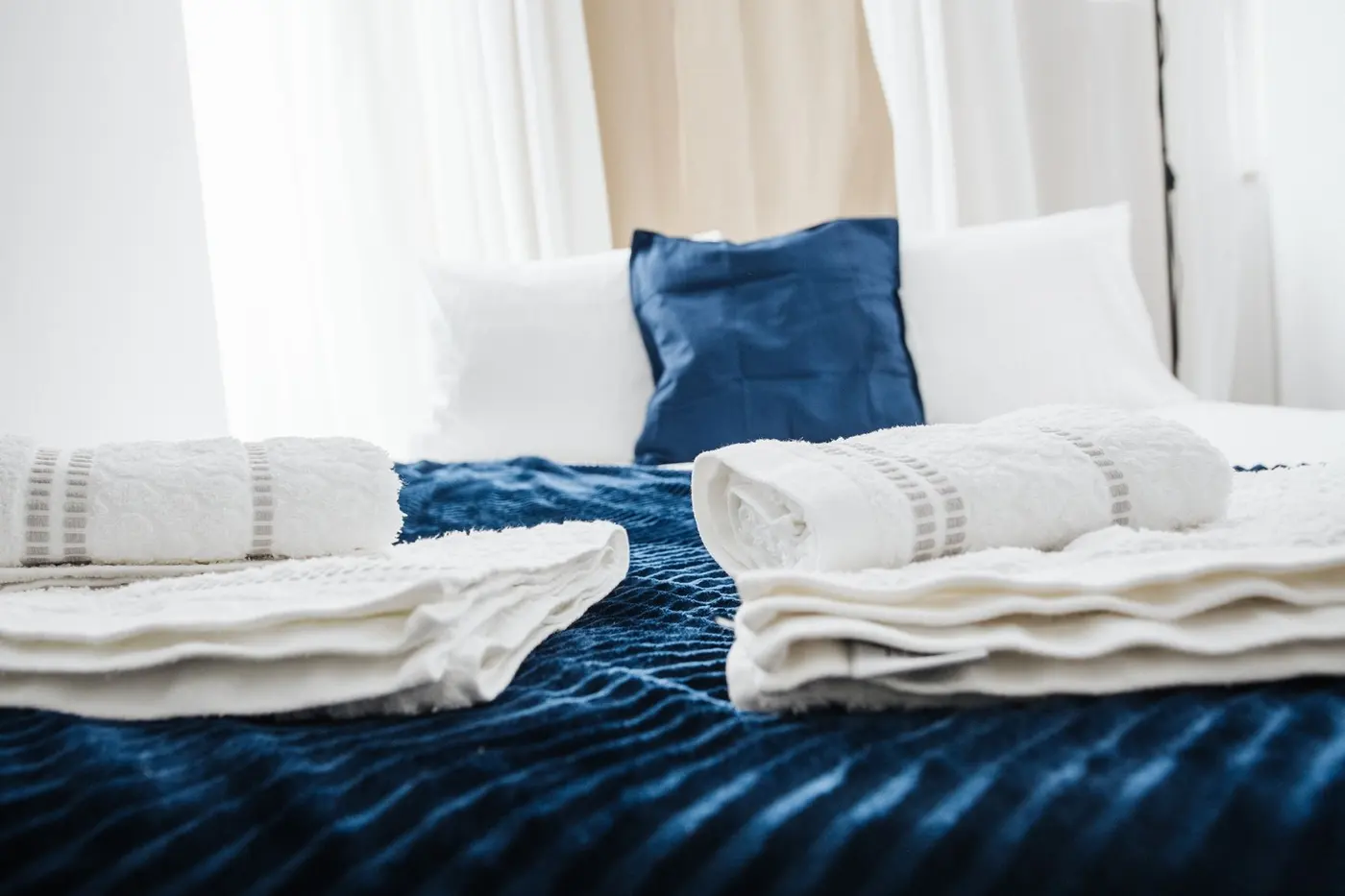 Připravené lůžko s čistými bílými ručníky po úklidu Airbnb