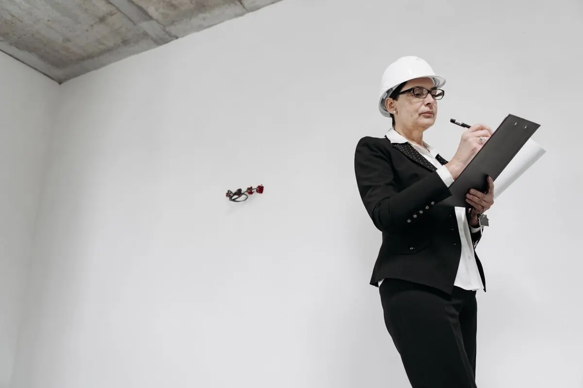 Technická pracovnice zapisuje stav stěny v prázdném bytě před odborným posouzením vlhkosti.